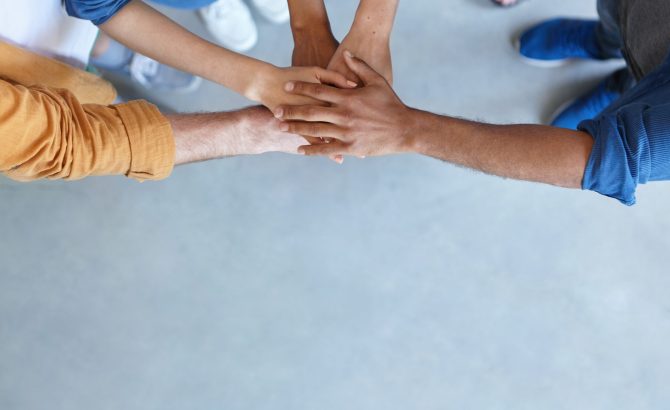 Friendship, partnership, togetherness, collaboration concept. Group of international friends stacking their hands expressing their friendship, agreement and support. People piling their hands